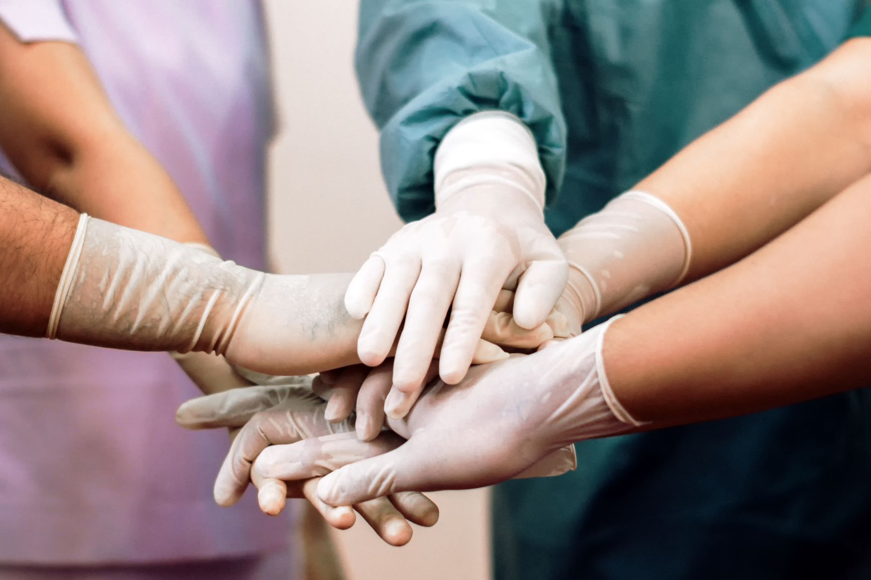 Hands in white medical gloves touching in a circle