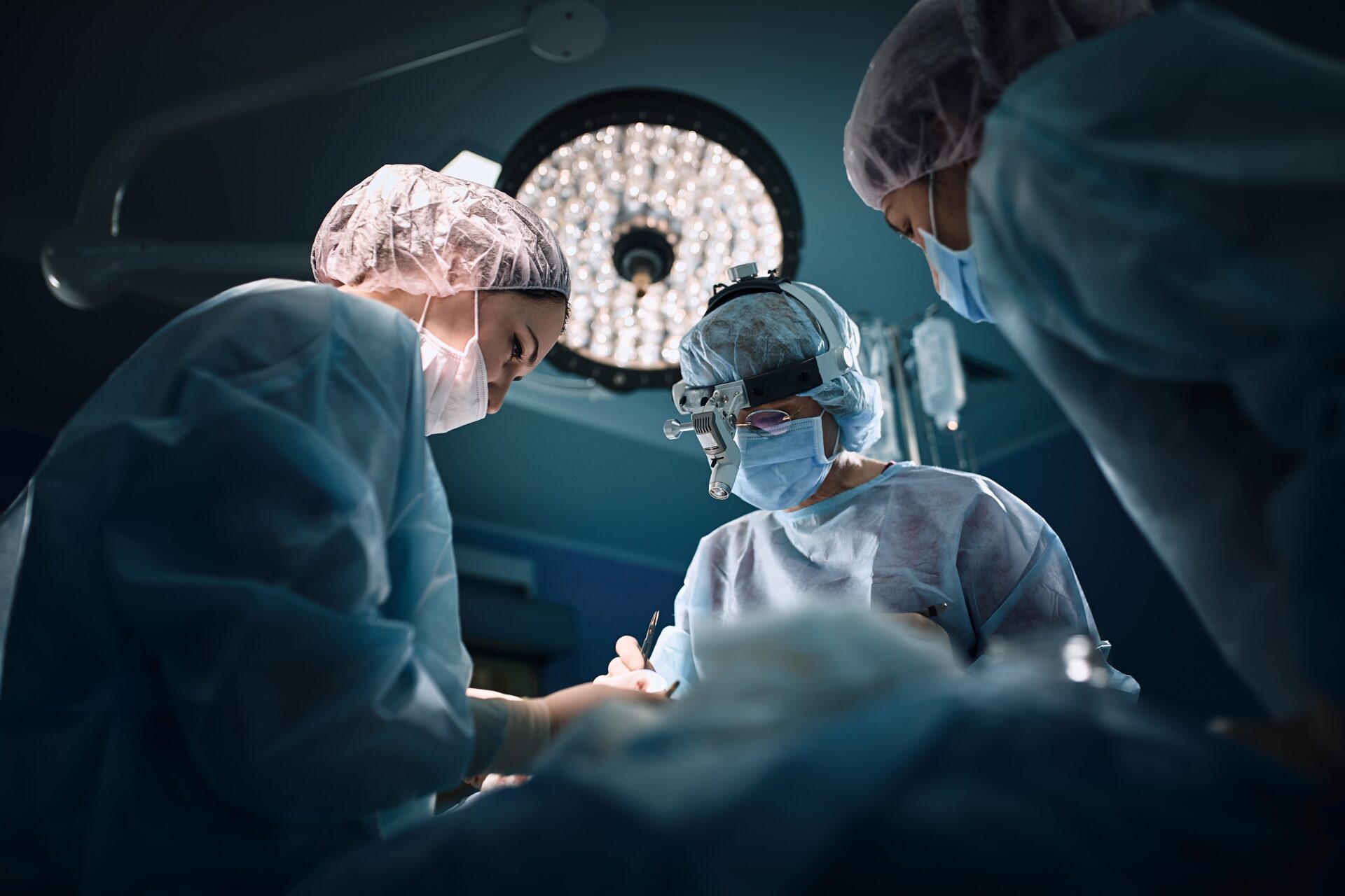 Medical team in the operating room, dark background. The theater of the operating room, an international team of professional doctors in a modern operating room are conducting an operation. Saving lives, modern medicine, blue blue light.