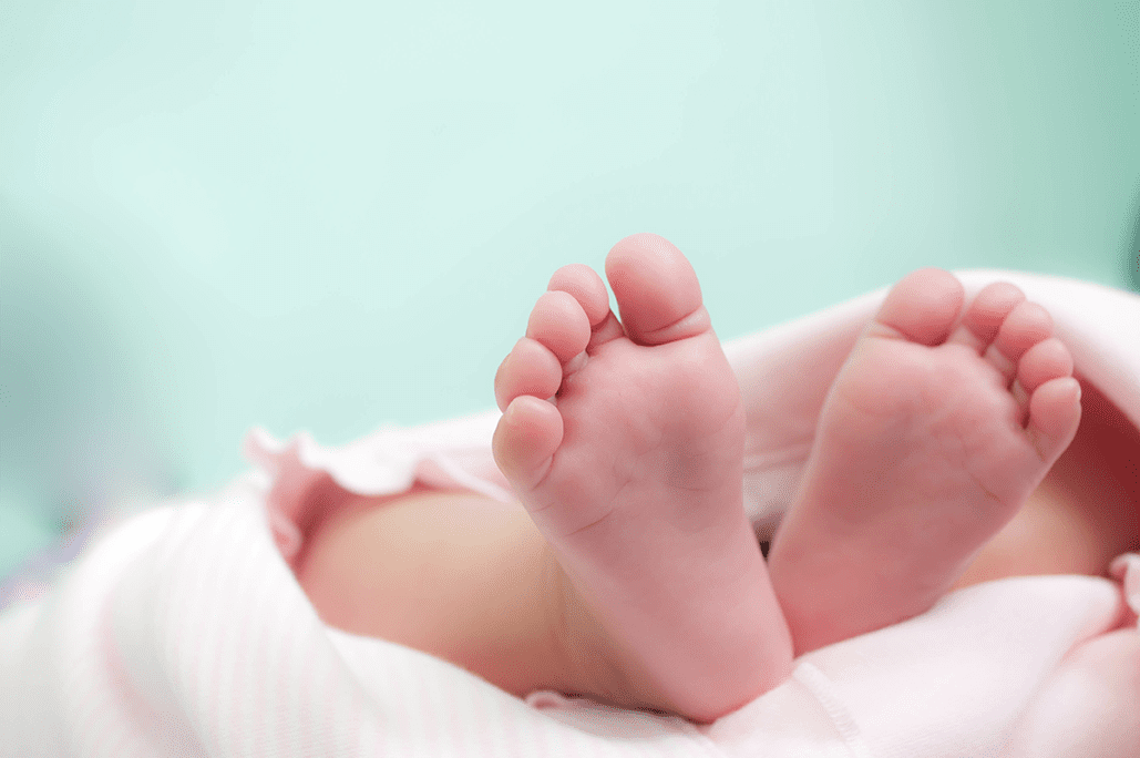 Photo showing soles of baby's feet under a blanket