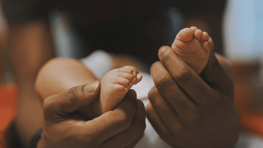 Adult hands holding feet of baby